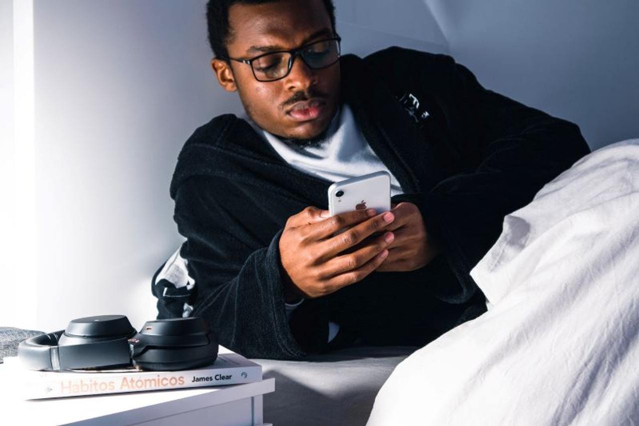 Man scrolls on his phone while in bed